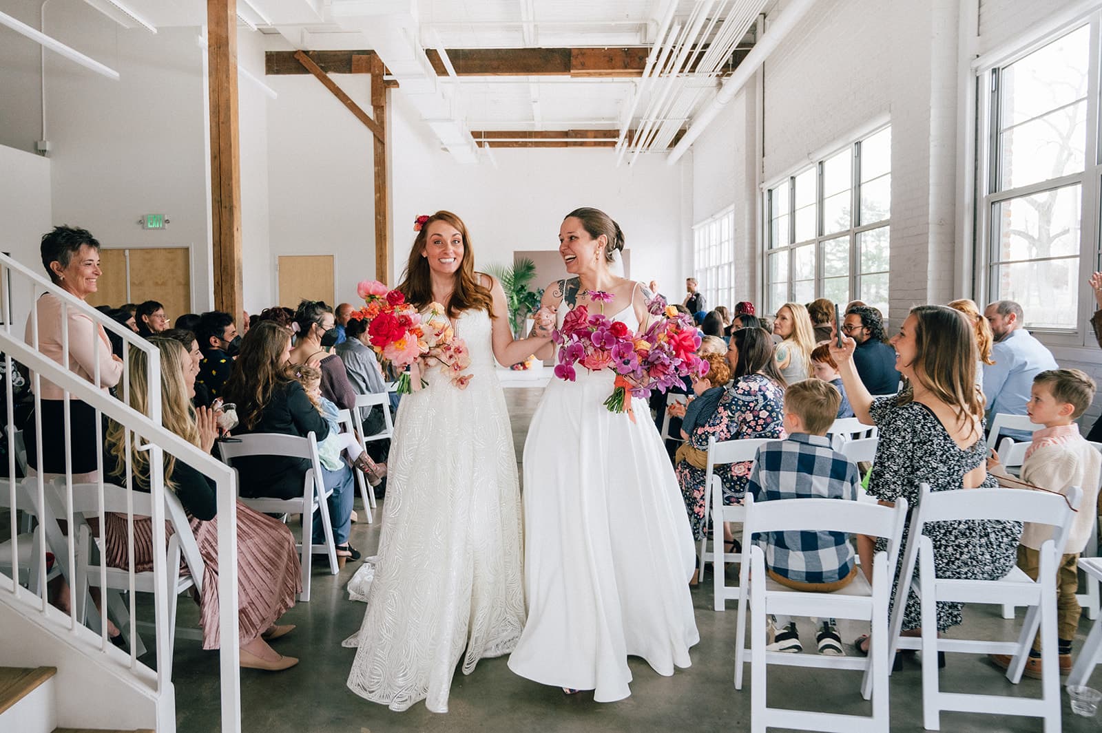 Newly weds in white dresses and bright bouquets walk down the isle